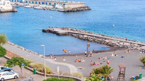 Zona costera con muelle, playa y aparcamiento.