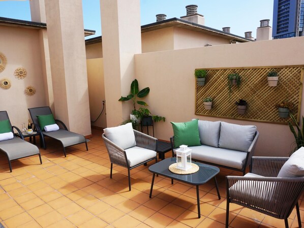 A sunlit outdoor seating area with a sofa, chairs, and a table. - Rooftop Cityview Classic Suite (Santa Cruz de Tenerife)