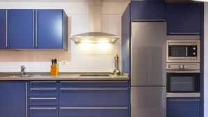 A modern kitchen with blue cabinets, stainless steel appliances, and a built-in oven. - Rooftop Cityview Classic Suite (Santa Cruz de Tenerife)