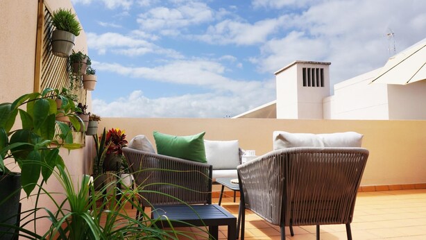 A patio with wicker furniture, potted plants, and a clear sky. - Rooftop Cityview Classic Suite (Santa Cruz de Tenerife)