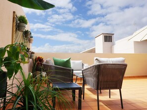 A patio with wicker furniture, potted plants, and a clear sky. - Rooftop Cityview Classic Suite (Santa Cruz de Tenerife)