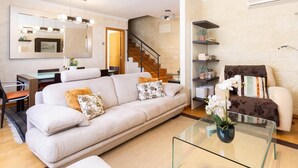 A modern living room with a sofa, coffee table, and a staircase leading to another level. - Rooftop Cityview Classic Suite (Santa Cruz de Tenerife)