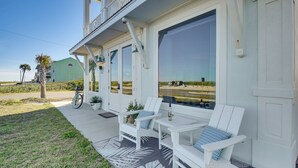 A covered porch with white Adirondack chairs and a table, overlooking a beach. - Oceanfront Flagler Beach Unit w/ Water Views! (Flagler Beach)