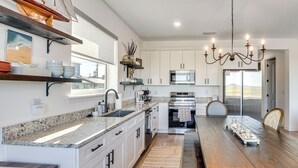 A modern kitchen with white cabinets, granite countertops, and stainless steel appliances. - Oceanfront Flagler Beach Unit w/ Water Views! (Flagler Beach)