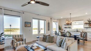 A spacious living room with a large sofa, a dining area with a table, and a kitchen in the background. - Oceanfront Flagler Beach Unit w/ Water Views! (Flagler Beach)