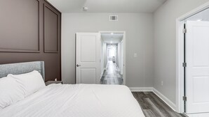 A bedroom with a bed, a ceiling fan, a door leading to a hallway, and a white door on the right. - < 2 Mi to Jackson Square: New Orleans Home w/ Yard (New Orleans)