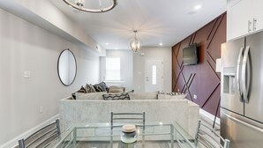 A modern kitchen with a central island, stainless steel appliances, and a dining area with a glass table. - < 2 Mi to Jackson Square: New Orleans Home w/ Yard (New Orleans)