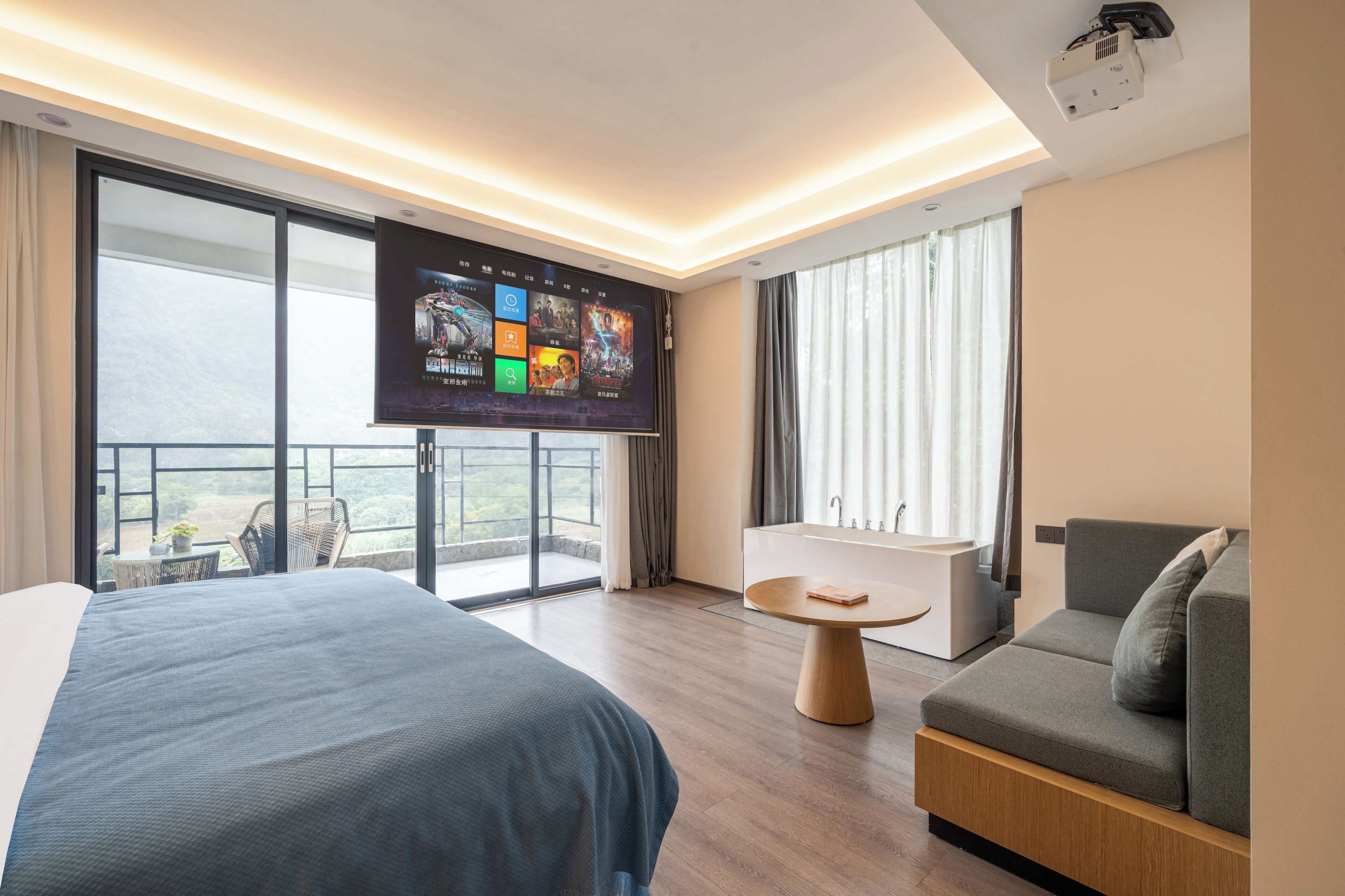Habitación de hotel moderna con una cama grande, un sofá, una mesita, un televisor y un balcón con vistas.