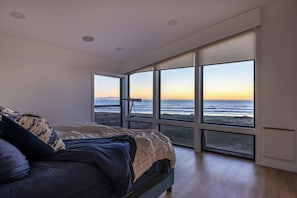 Una camera da letto con un'ampia finestra vista mare, un letto con vista e un telescopio su un treppiede.