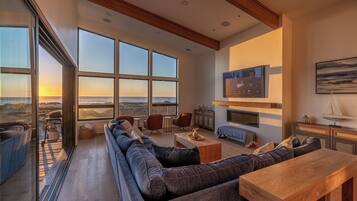 A spacious living room with a large sofa, a wooden coffee table, and a TV mounted on the wall.