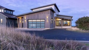 A modern two-story house with a garage, large windows, and a well-maintained lawn.