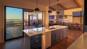A modern kitchen with a large island, stainless steel appliances, and a view of the ocean.