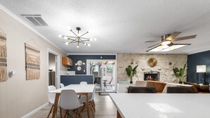 A modern dining area with a white table, chairs, and a ceiling fan.