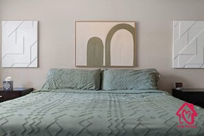 Un dormitorio con cama, dos mesitas de noche, un reloj de pared y arte abstracto en la pared.
