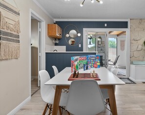 A dining area with a table set for four, a chessboard, and board games.