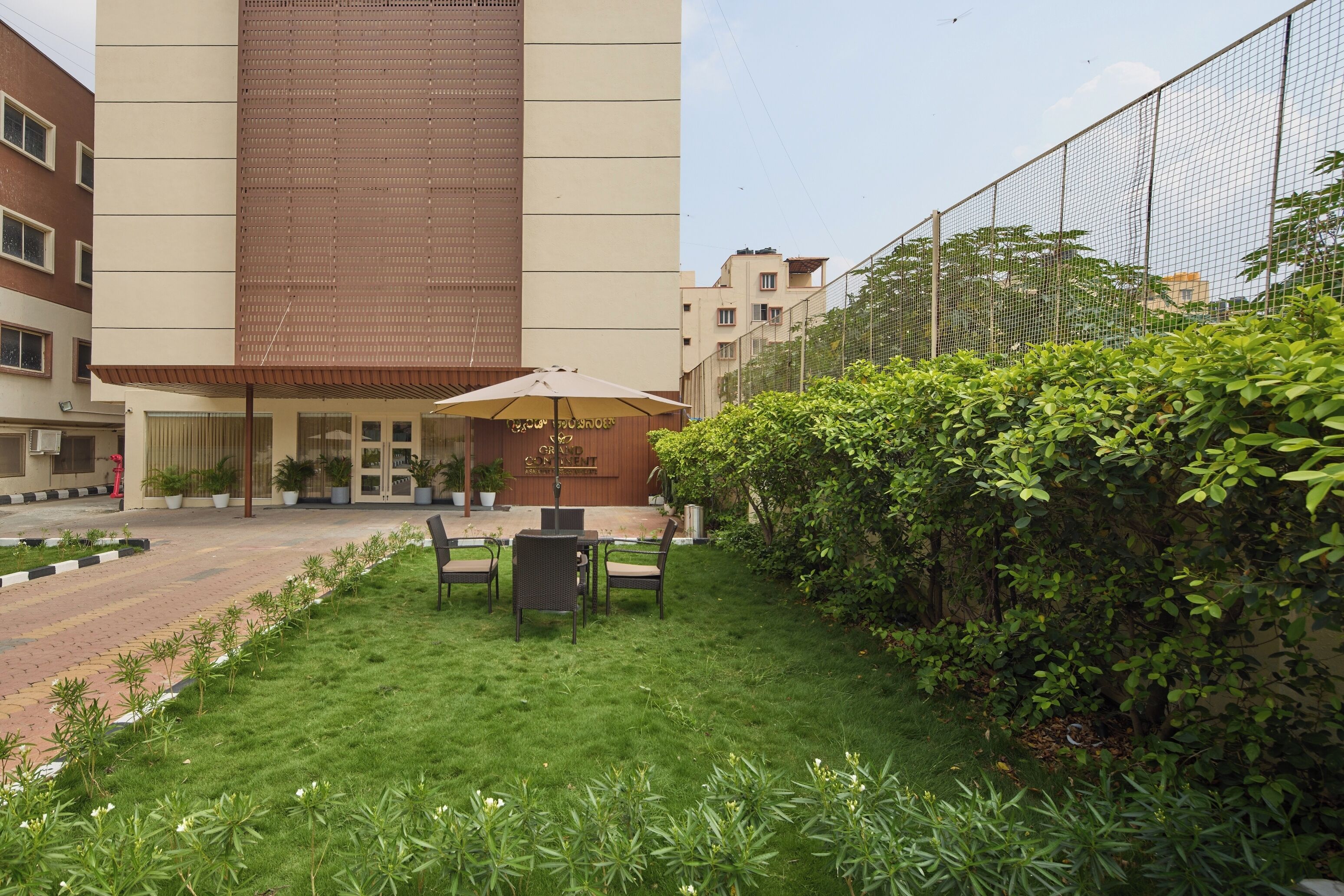 A hotel courtyard with a seating area, a wooden fence, and a building entrance.