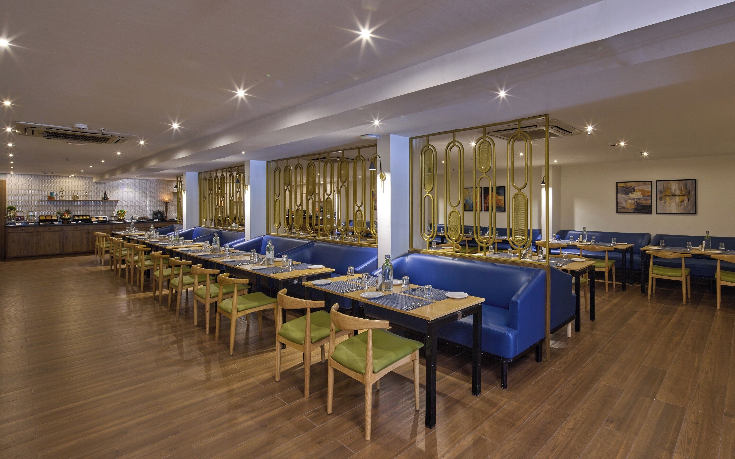 A restaurant with long tables, blue booths, and wooden chairs.