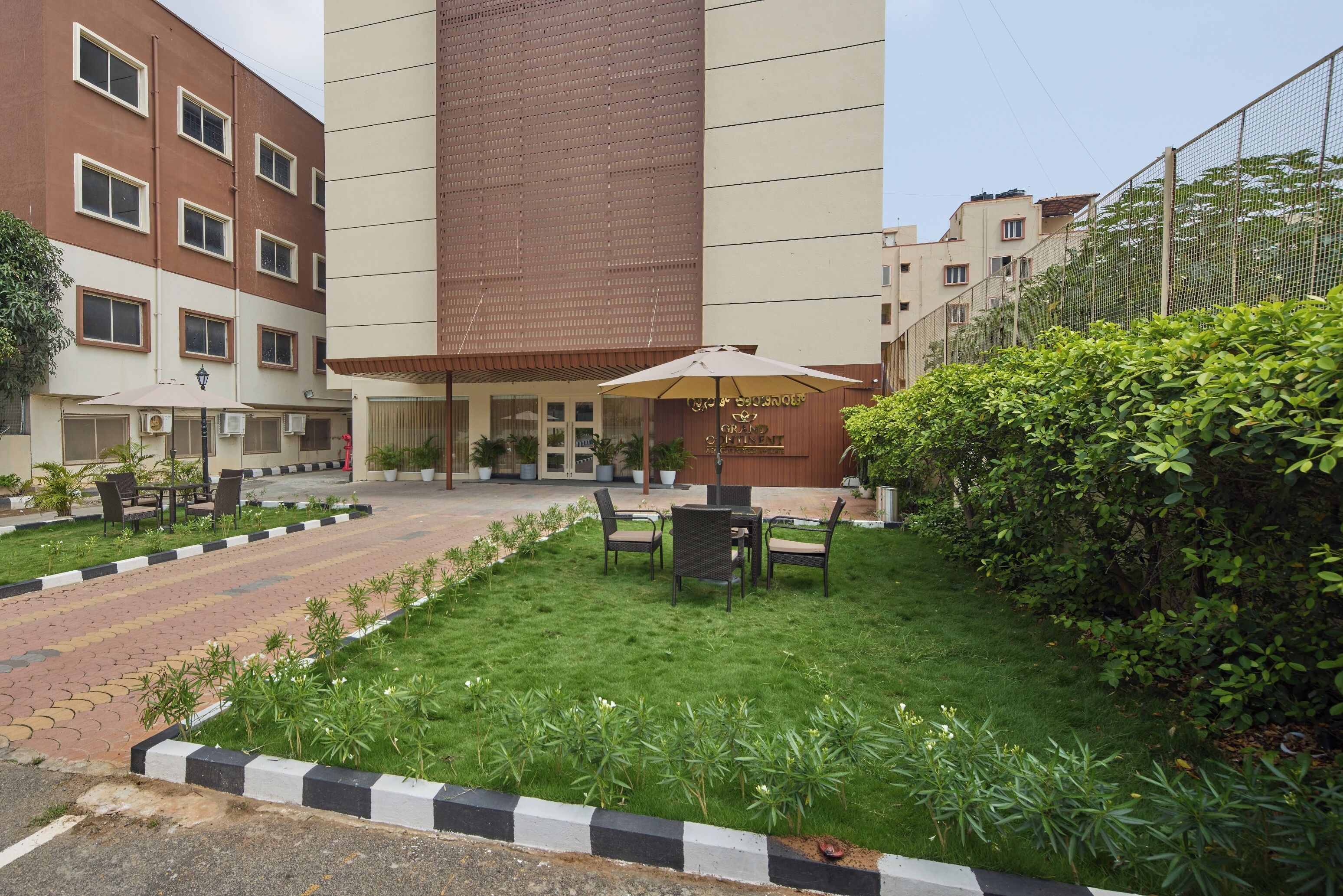 A courtyard with a seating area, a building with multiple windows, and a sign that reads "Grand Hotel."