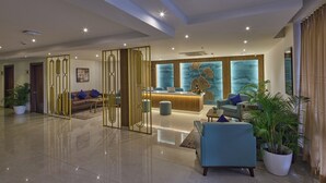 A spacious lobby with a reception desk, seating area, and decorative elements. - Grand Continent Brookefield – A Sarovar Portico Affiliate Hotel (Bengaluru)