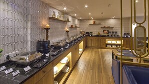 A modern restaurant with a long counter, wooden shelves, and a decorative wall pattern. - Grand Continent Brookefield – A Sarovar Portico Affiliate Hotel (Bengaluru)