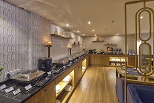 A modern restaurant with a long counter, wooden shelves, and a decorative wall pattern.