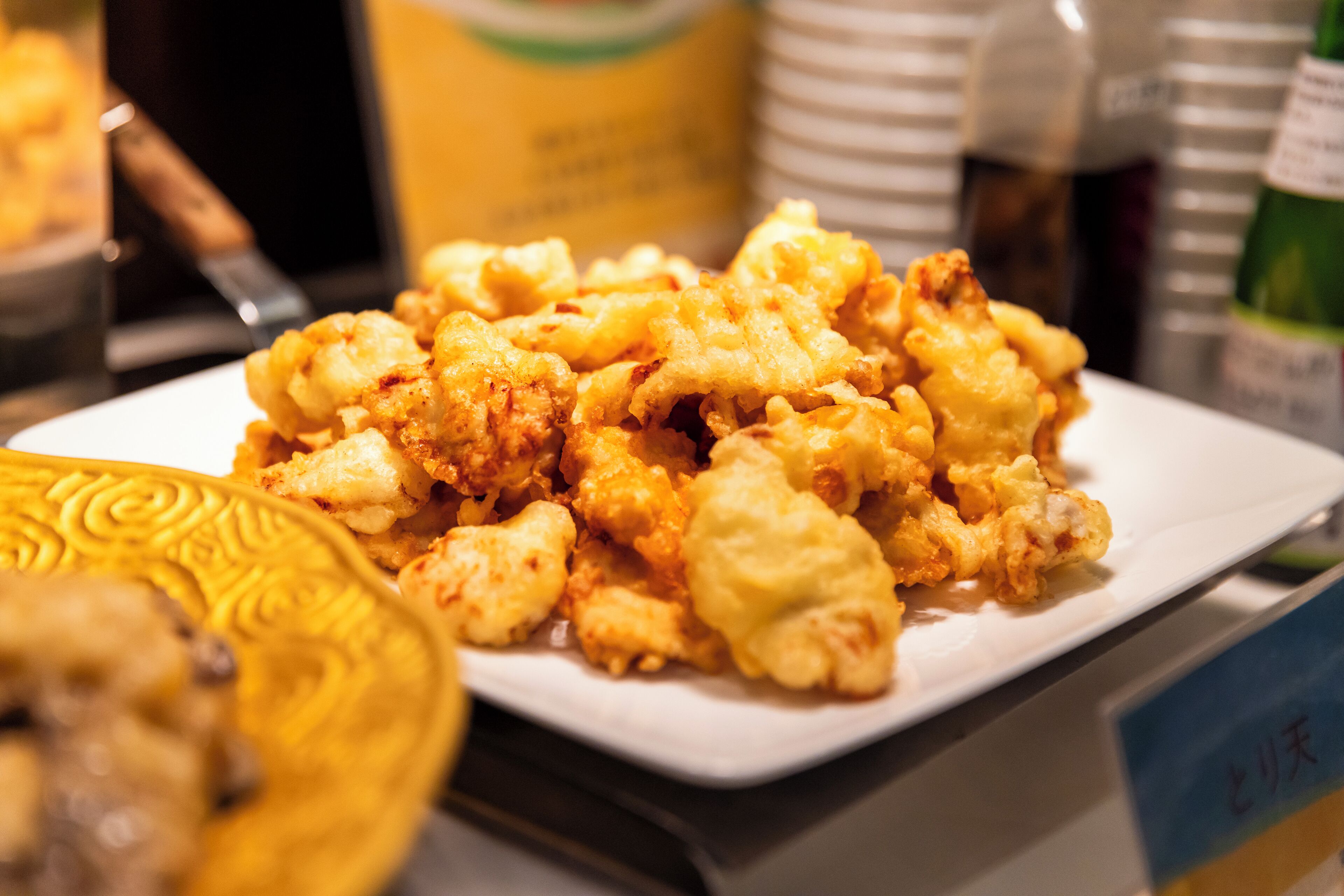 A plate of fried food on a table with a decorative plate and a sign with text.