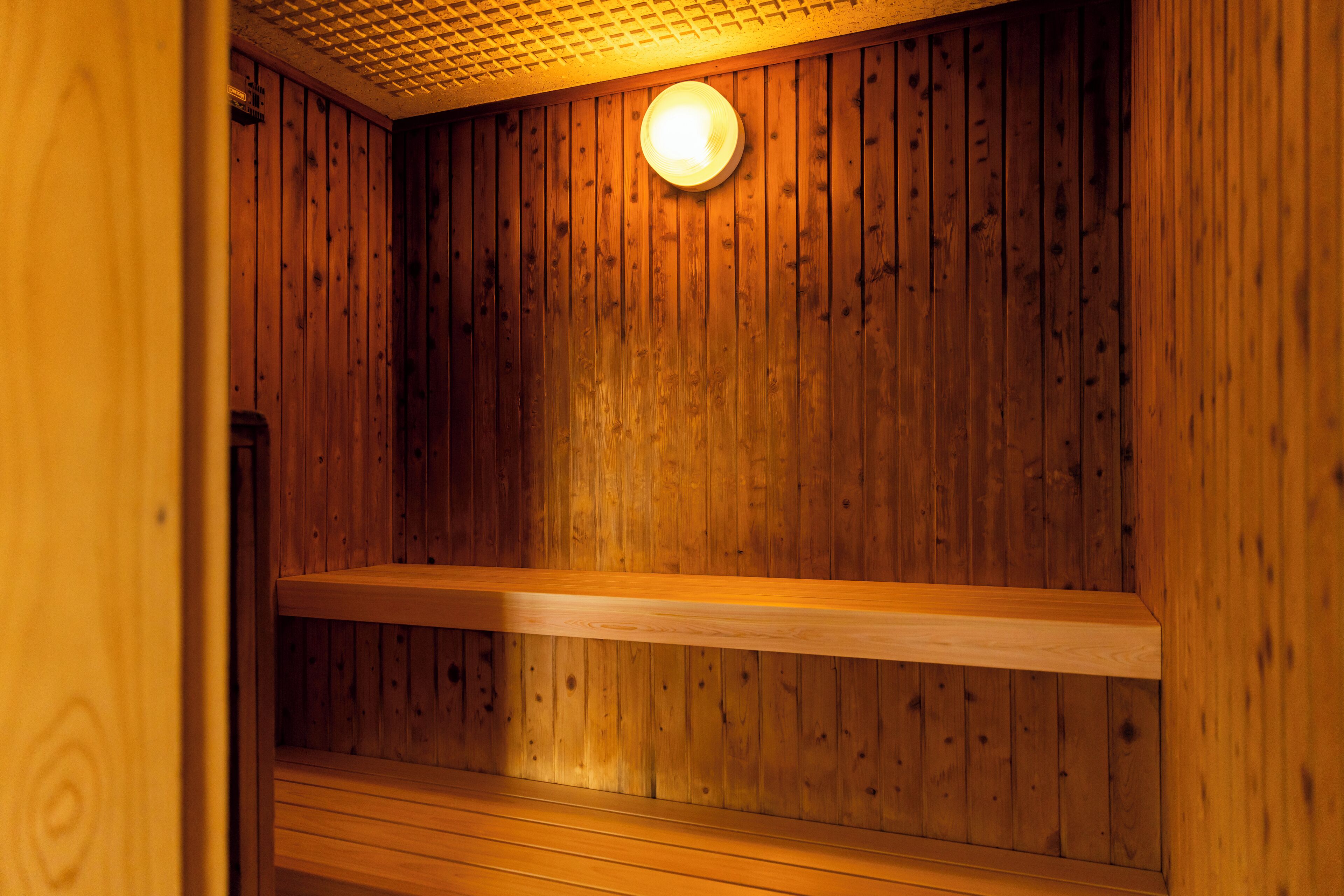 Un sauna en bois avec un seul banc et un luminaire au plafond.