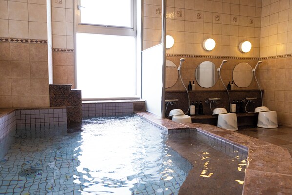 Un baño con una piscina pequeña, varios lavamanos y un ventanal que proporciona luz natural.