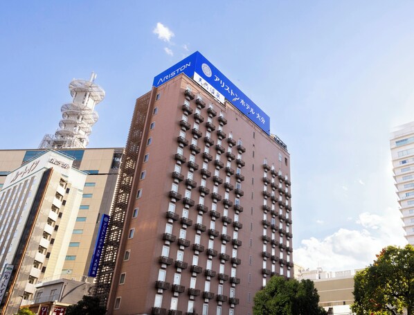 Un edificio de gran altura con un letrero azul destacado en la parte superior, múltiples balcones y una estructura de torre a la izquierda.
