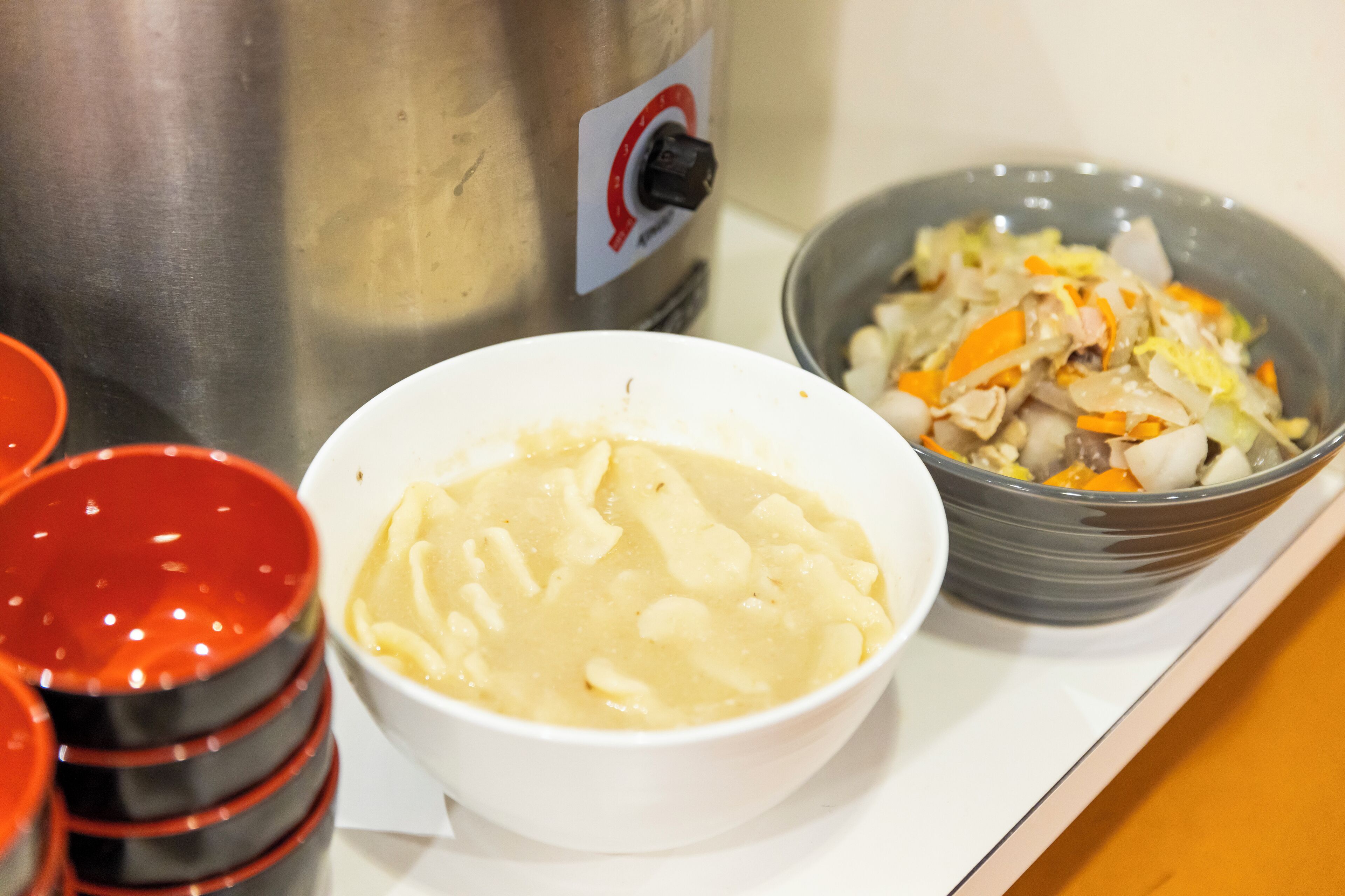 Een aanrecht met een schaal aardappelpuree, een schaal gemengd groenterecht en een roestvrijstalen apparaat.