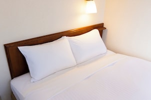 Una cama bien tendida con sábanas blancas y un cabecero de madera.