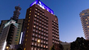 Un grand hôtel avec une enseigne bien visible au sommet, de nombreux balcons et une tour située sur le côté gauche.