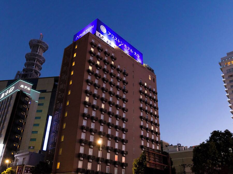 Un grand hôtel avec une enseigne bien visible au sommet, de nombreux balcons et une tour située sur le côté gauche.