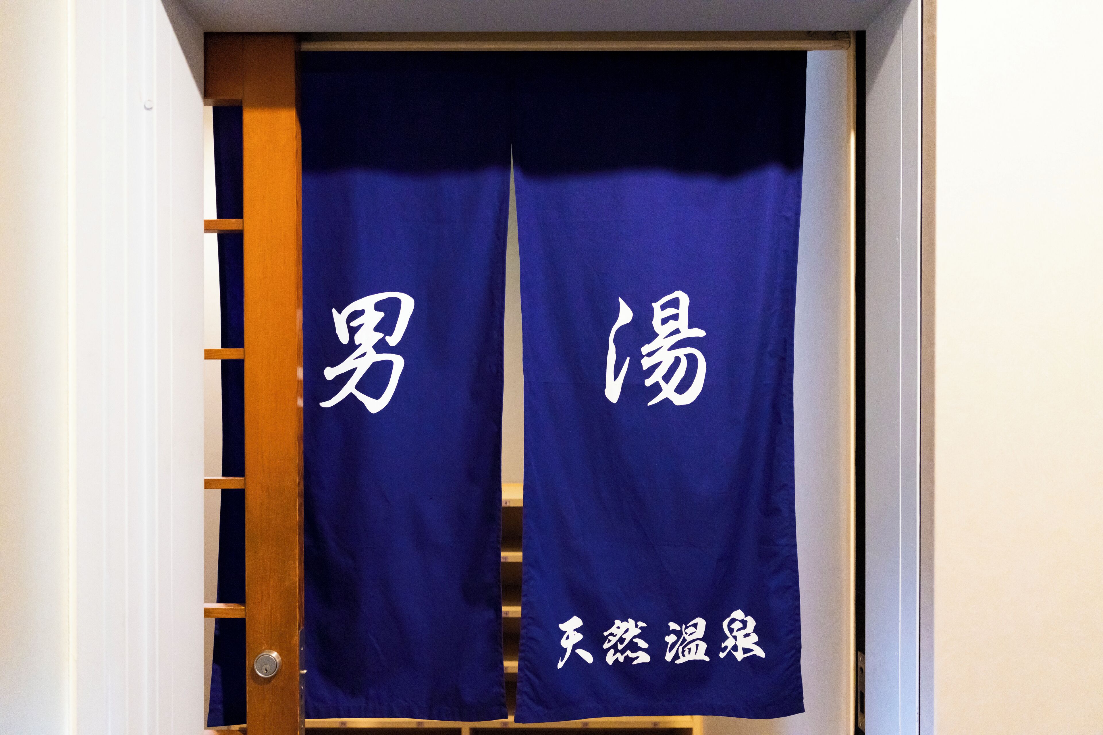 Una habitación con una puerta de madera y dos cortinas azules con texto blanco.
