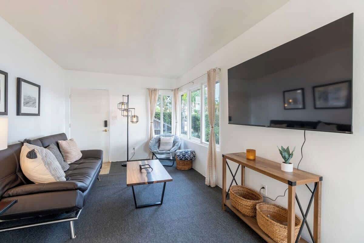 A modern living room with a sofa, a coffee table, a TV, and a window with curtains.