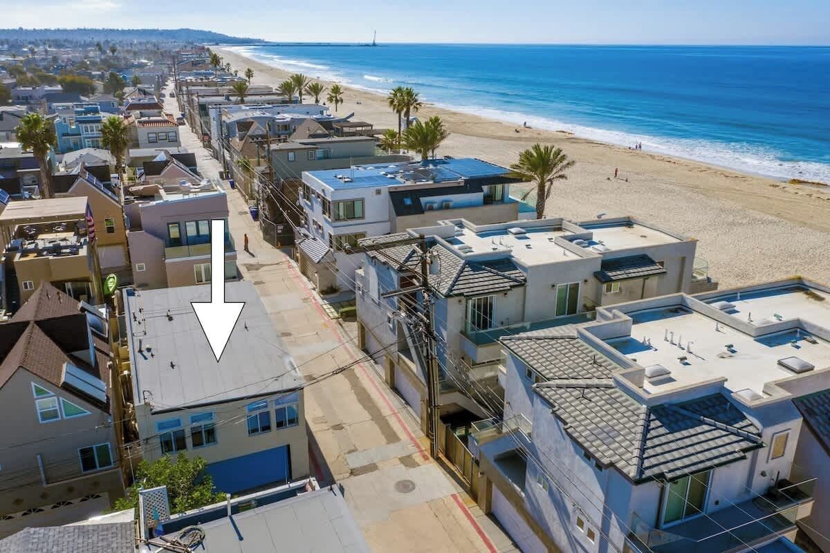 Una zona residencial costera con casas modernas, una playa y una vista despejada del océano.
