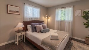 A neatly arranged bedroom with a bed, bedside table, lamp, and a framed picture on the wall. - Hot Tub Family Home with Mountain Views - Close to Red Rocks and Clear Creek! (Golden)