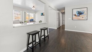 A spacious kitchen with a white countertop, two black barstools, and a window with blinds. - Hot Tub Family Home with Mountain Views - Close to Red Rocks and Clear Creek! (Golden)