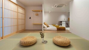 A traditional Japanese-style room with tatami flooring, a shoji screen, and a futon bed. - KUTSUROGI SAUNA and STAY (Tokyo)