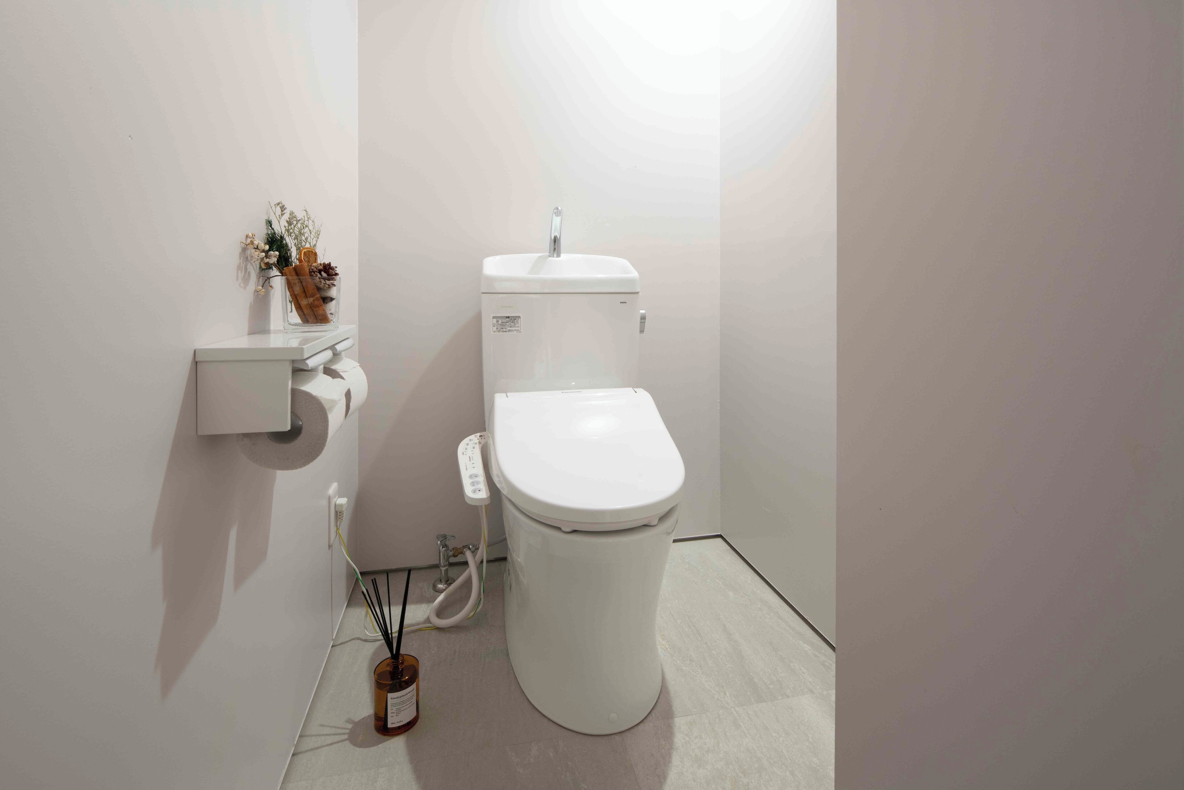 A modern bathroom with a white toilet, a small sink, and a wall-mounted toilet paper holder.