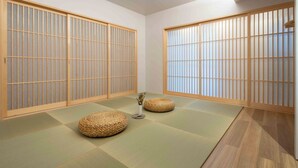 A traditional Japanese room with tatami flooring, shoji screens, and woven tatami mats. - KUTSUROGI SAUNA and STAY (Tokyo)