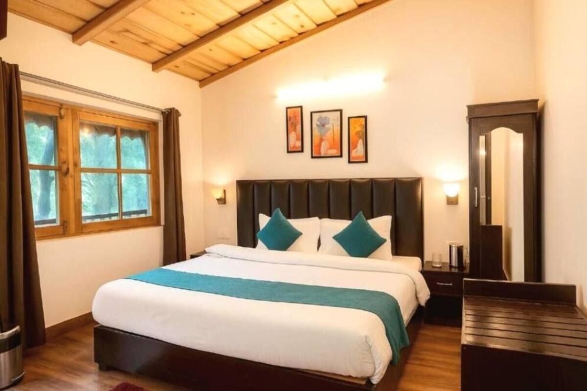 A bedroom with a large bed, wooden headboard, and a window with curtains.
