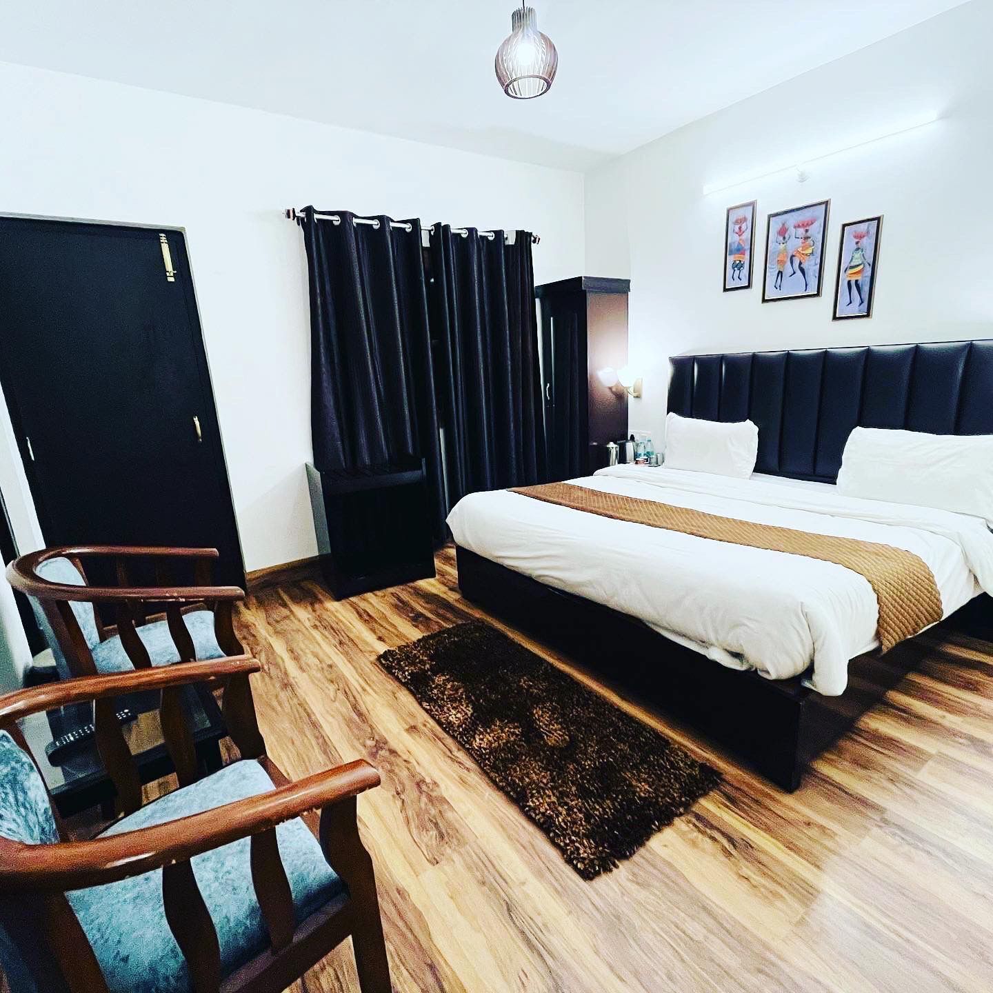 A hotel room with a bed, a chair, a desk, and a wardrobe.