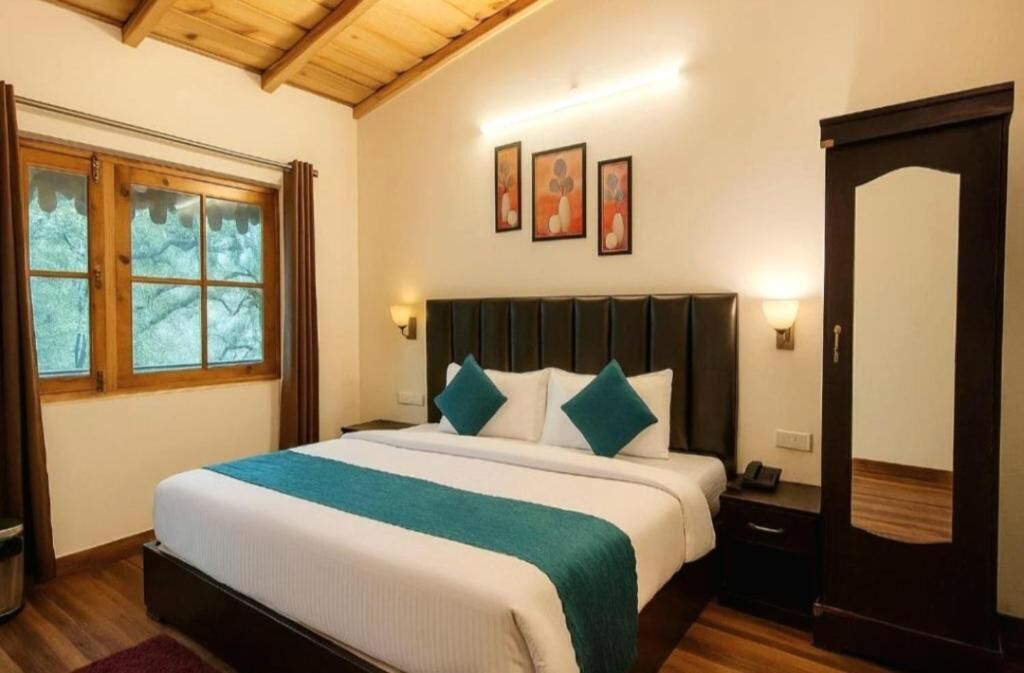 A hotel room with a large bed, a wooden ceiling, a window with curtains, and a door.