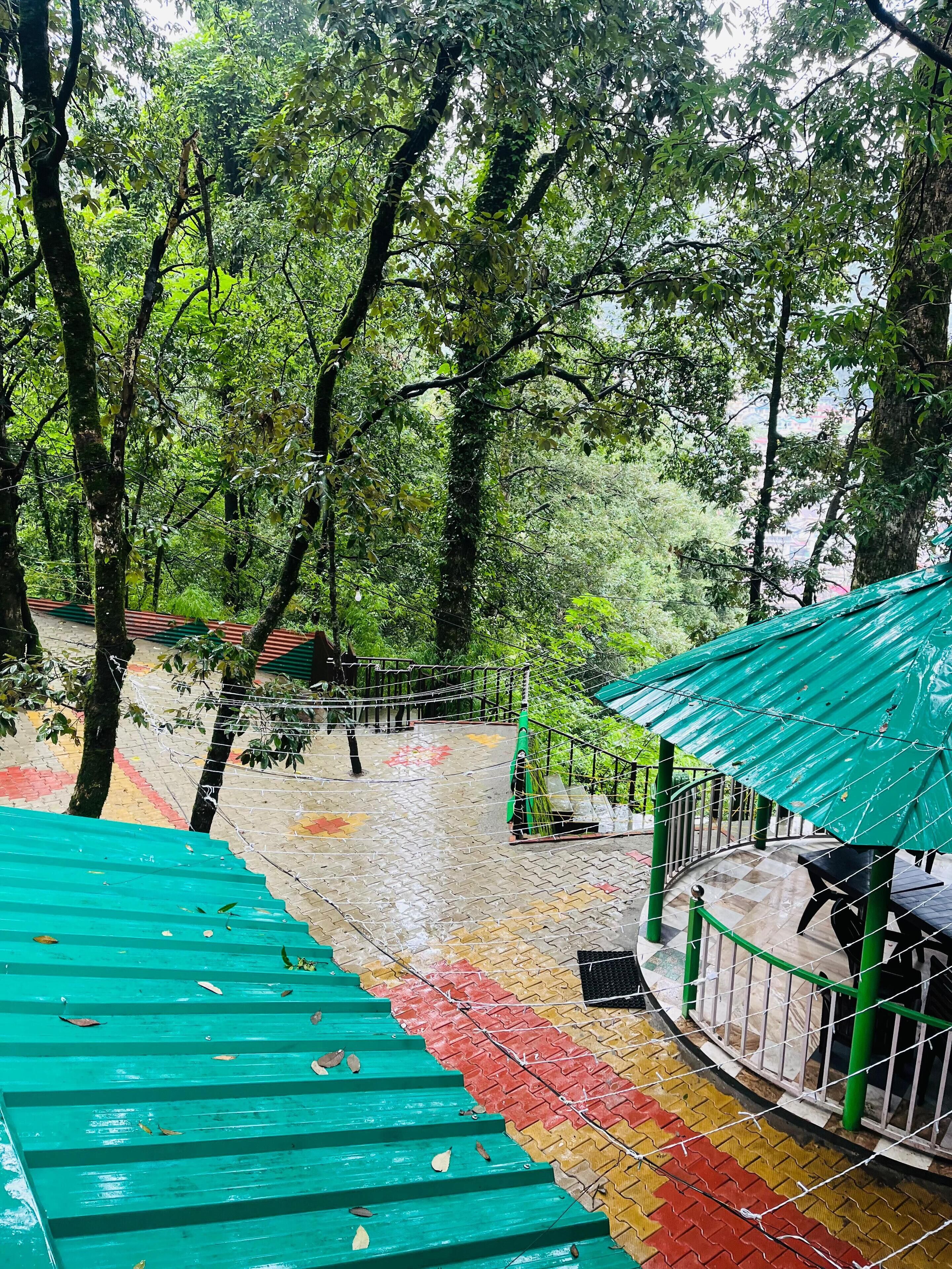 A staircase leading up to a green-roofed structure surrounded by trees.