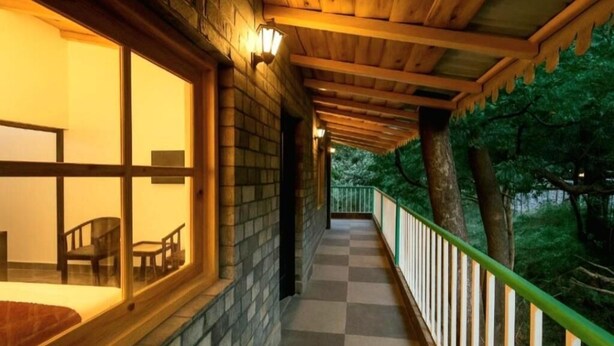 A corridor with a checkered floor, wooden ceiling, and a railing on one side.