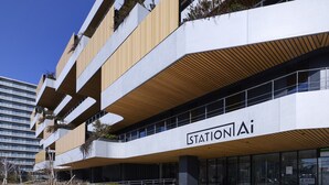 Un edificio de varios pisos con un diseño arquitectónico moderno, que presenta un llamativo letrero 'StationAi' en la fachada.