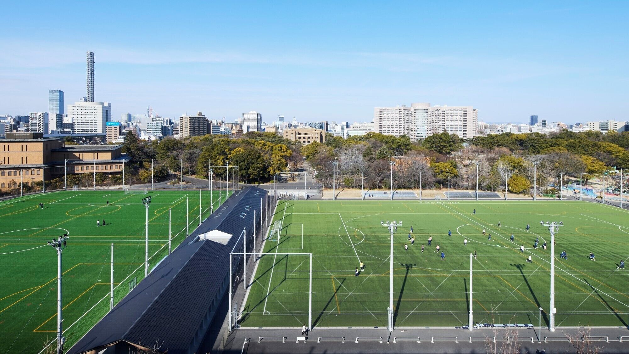 A large sports field with multiple sports fields, surrounded by buildings and trees.
