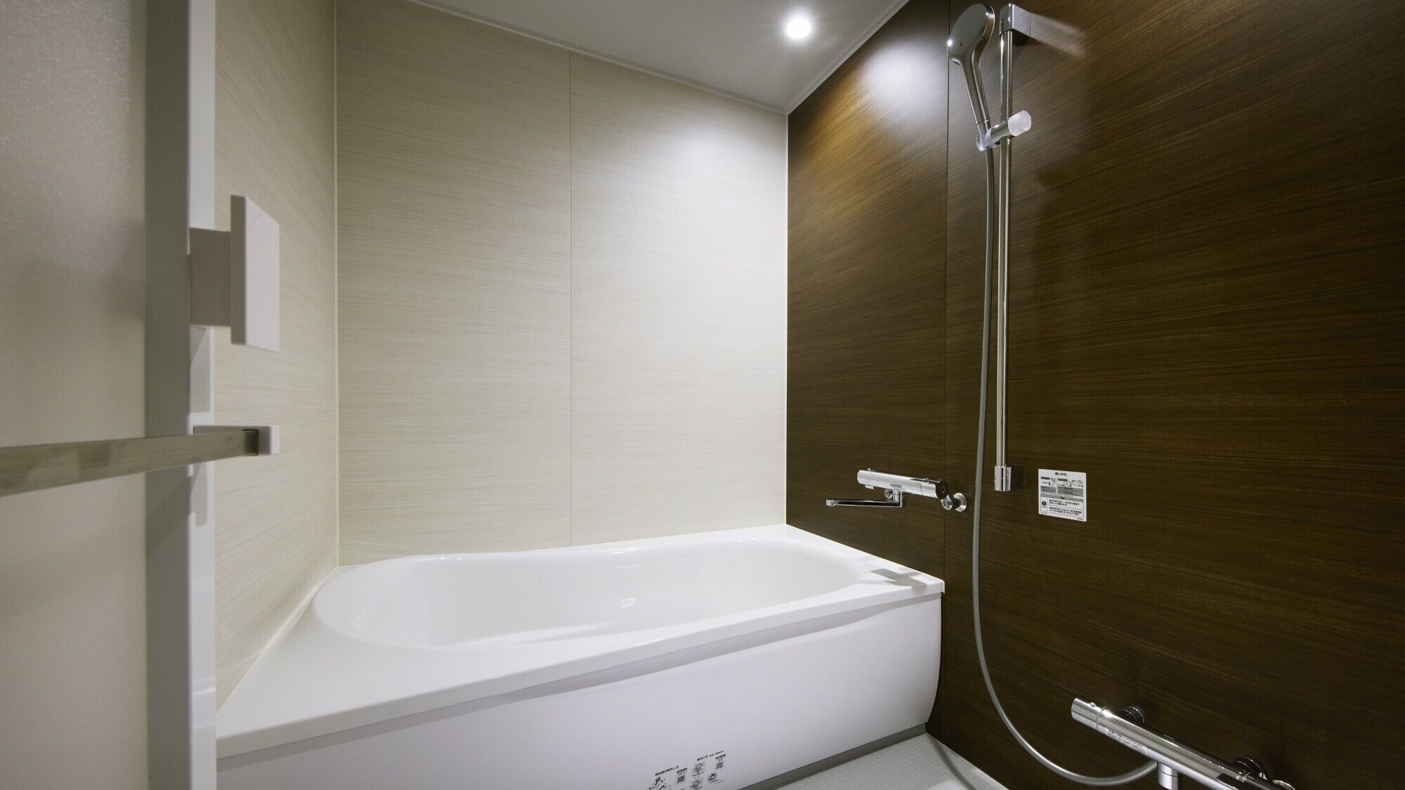 A modern bathroom with a white bathtub, a wooden wall, and a shower with a handheld showerhead.