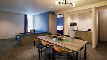 A modern apartment with a dining area, kitchenette, and a living space with a sofa and a window.